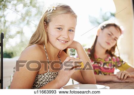 Stock Image - Girls eating fresh fruit. Fotosearch