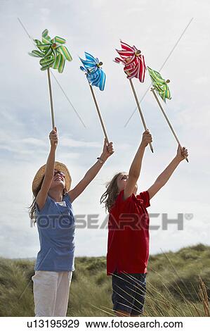 Girls holding up windmills in the sky View Large Photo Image Stock Photo - Girls holding up windmills in the sky. Fotosearch