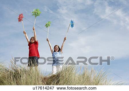 Stock Photo - Girls holding up windmills in the sky. Fotosearch