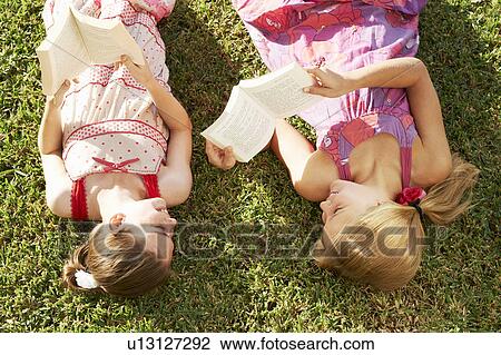 Girls lying on grass reading books View Large Photo Image Stock Image - Girls lying on grass reading books. Fotosearch