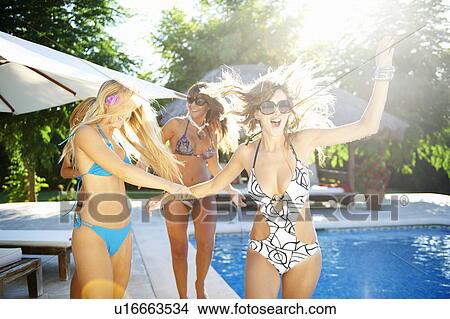 Girls playing by the pool in swimsuits View Large Photo Image Picture - Girls playing by the pool in swimsuits. Fotosearch