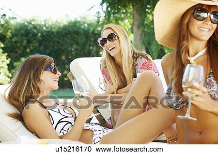 Girls relaxing by the pool on sun beds View Large Photo Image Stock Image - Girls relaxing by the pool on sun beds. Fotosearch
