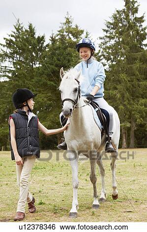 Girls riding a pony View Large Photo Image Stock Photograph - Girls riding a pony. Fotosearch