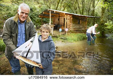 Stock Photograph - Grandfather and boy with sailing boat. Fotosearch