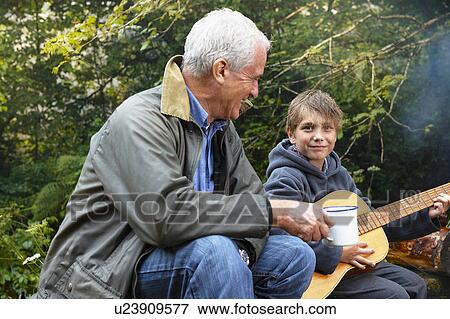 Grandfather and grandson by campfire View Large Photo Image Stock Photo - Grandfather and grandson by campfire. Fotosearch