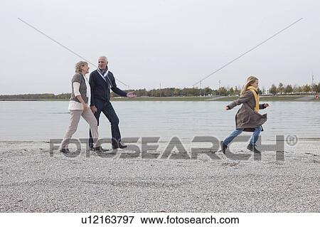 Stock Photo - Grandparents and girl walking by lake. Fotosearch