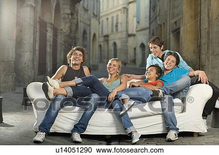 Stock Image - Group relax on couch laughing in street. Fotosearch