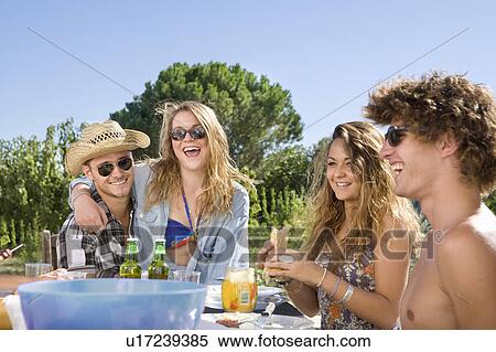 Stock Photography - Group share a laugh at outdoor BBQ. Fotosearch