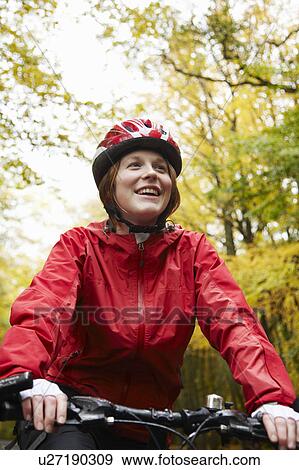 Stock Photo - Happy girl cycling surrounded by trees. Fotosearch