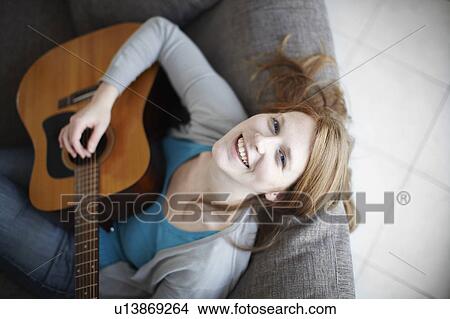 Happy girl playing guitar on sofa View Large Photo Image Picture - Happy girl playing guitar on sofa. Fotosearch
