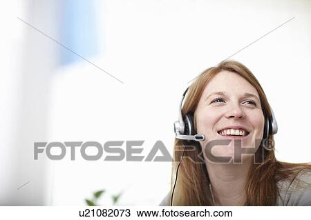 Stock Image - Happy girl with headset next to computer. Fotosearch