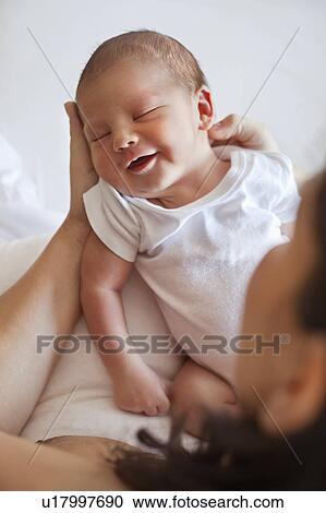 Stock Image - Happy sleeping baby in mothers arms. Fotosearch