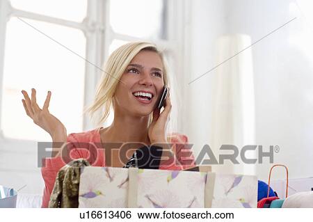 Stock Photograph - Happy woman on phone with shopping bags. Fotosearch