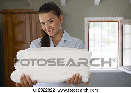 Hotel maid in room with pile of towels View Large Photo Image Stock Image - Hotel maid in room with pile of towels. Fotosearch