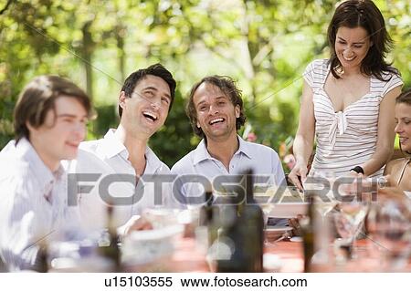 Stock Photography - Laughing people sitting on a table. Fotosearch