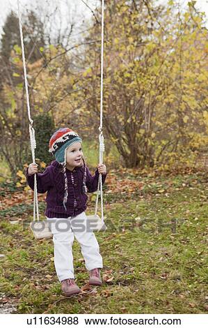 Little girl on a swing in the garden View Large Photo Image Stock Photo - Little girl on a swing in the garden. Fotosearch