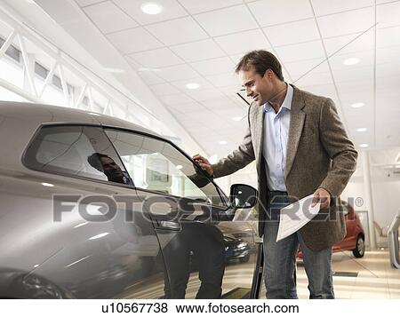 Male customer looks at car in dealership View Large Photo Image Stock Photo - Male customer looks at car in dealership. Fotosearch