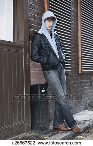 Stock Image - Male with hooded top waiting in street. Fotosearch
