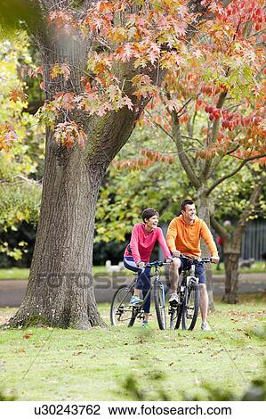 Man and woman cycling in the park View Large Photo Image Stock Image - Man and woman cycling in the park. Fotosearch
