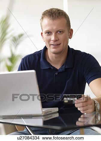 Picture - Man at home shopping online. Fotosearch
