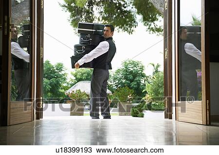 Man carrying suitcases into hotel View Large Photo Image Stock Image - Man carrying suitcases into hotel. Fotosearch