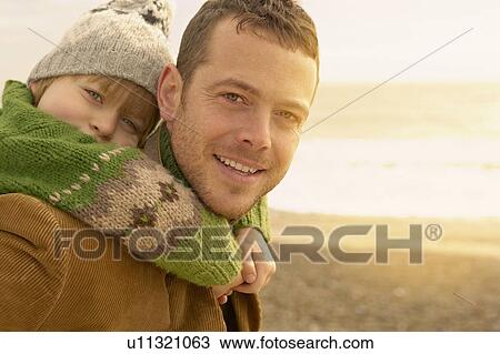 Man carrying young boy on beach. Autumn View Large Photo Image Stock Image - Man carrying young boy on beach. Autumn. Fotosearch