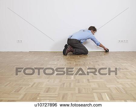 Stock Photograph - Man clears rubbish from empty flat. Fotosearch
