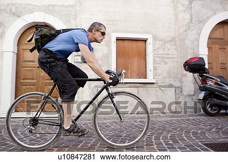 Man cycling through village View Large Photo Image Stock Image - Man cycling through village. Fotosearch