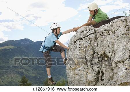 Man helping boy to get to the top View Large Photo Image Stock Photograph - Man helping boy to get to the top. Fotosearch