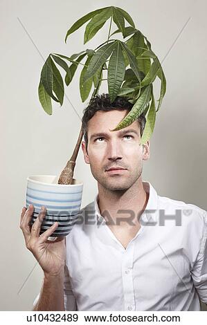 Stock Photo - Man holding indoor plant over his head. Fotosearch
