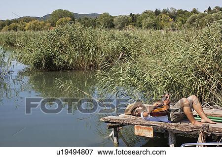 Man laying down on jetty with a guitar View Large Photo Image Stock Photo - Man laying down on jetty with a guitar. Fotosearch