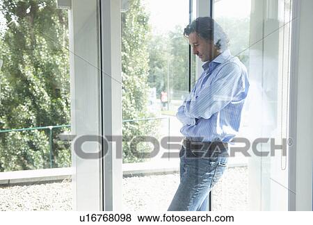Stock Photo - Man leaning on office windows, thinking. Fotosearch