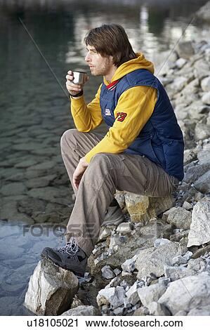 Stock Image - Man on lake drinking hot beverage. Fotosearch