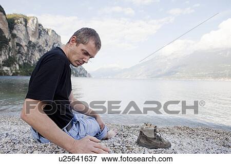 Stock Photo - Man on rocky beach. Fotosearch