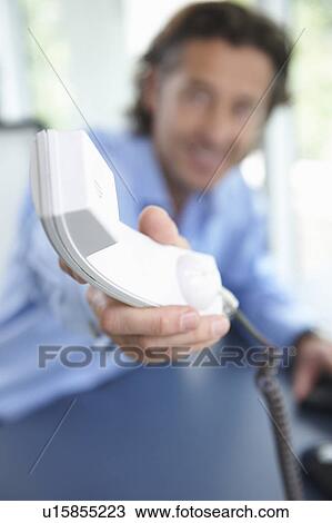 Stock Image - Man passing the phone, close up on horn. Fotosearch