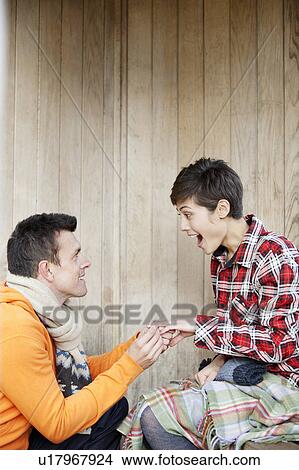 Picture - Man proposing to woman in a hut in park. Fotosearch