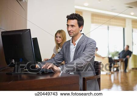 Stock Image - Man sitting at computer. Fotosearch