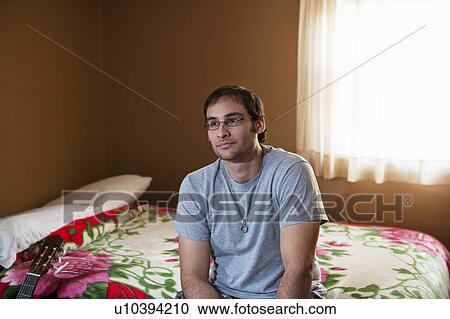 Stock Image - Man sitting on bed. Fotosearch