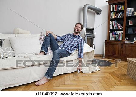 Man sitting on couch View Large Photo Image Stock Image - Man sitting on couch. Fotosearch