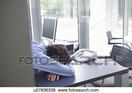 Stock Photo - Man sleeping on his office desk. Fotosearch