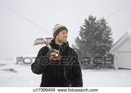 Stock Photo - Man standing with snow shovel on sholder. Fotosearch