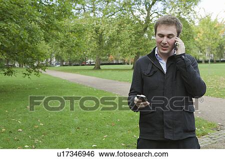 Man using two mobile phones View Large Photo Image Stock Photograph - Man using two mobile phones. Fotosearch