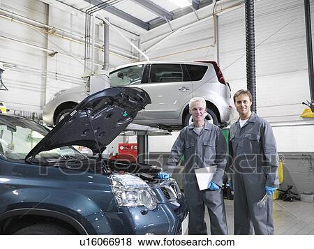 Mechanics working in car dealership View Large Photo Image Stock Photo - Mechanics working in car dealership. Fotosearch