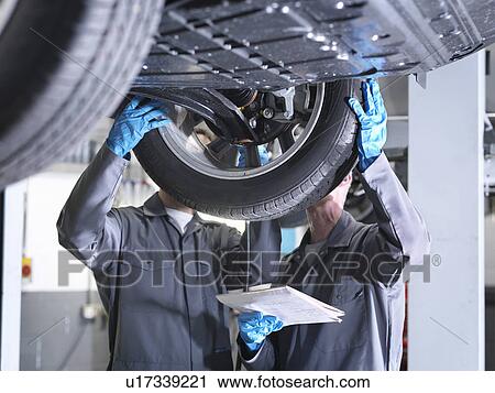 Stock Image - Mechanics working under car. Fotosearch