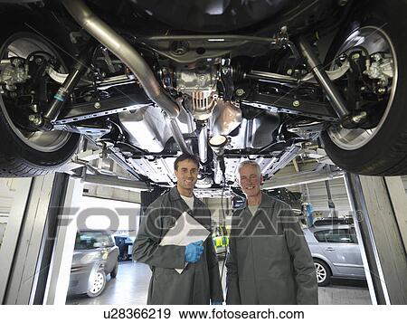 Mechanics working under car View Large Photo Image Stock Photo - Mechanics working under car. Fotosearch