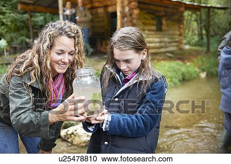 Stock Image - Mom and daughter examining insect in jar. Fotosearch