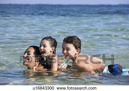 Mother + 2 kids on her back in the water View Large Photo Image Stock Image - Mother + 2 kids on her back in the water. Fotosearch
