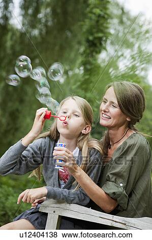 Stock Photo - Mother and daughter blowing bubbles. Fotosearch