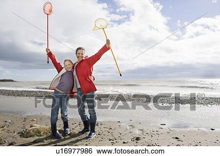 Stock Photograph - Mother and daughter holding up fishnets. Fotosearch