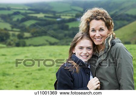 Mother and daughter hugging in field View Large Photo Image Stock Photo - Mother and daughter hugging in field. Fotosearch